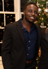 photograph of David Akinsooto in front of window and a decorated tree