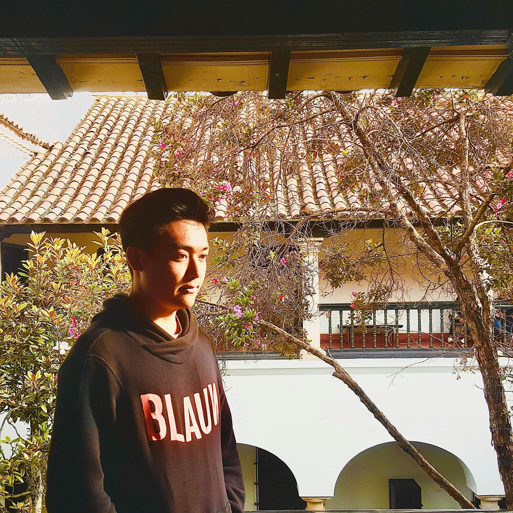 photograph of Chris standing in front of a tree and building