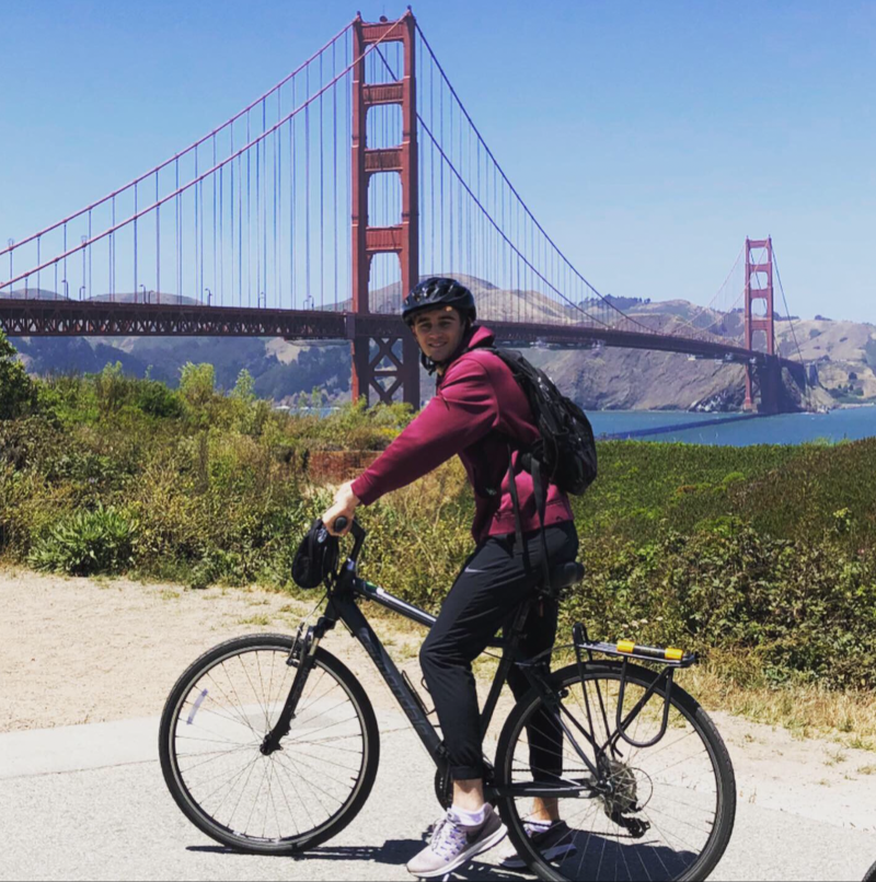 photograph of Jonah Covitz riding a bicycle in front of the Golden Gate bridge