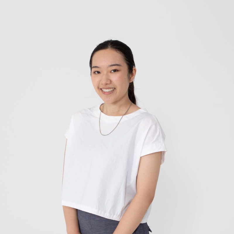 photograph of Mai standing in front of a white wall